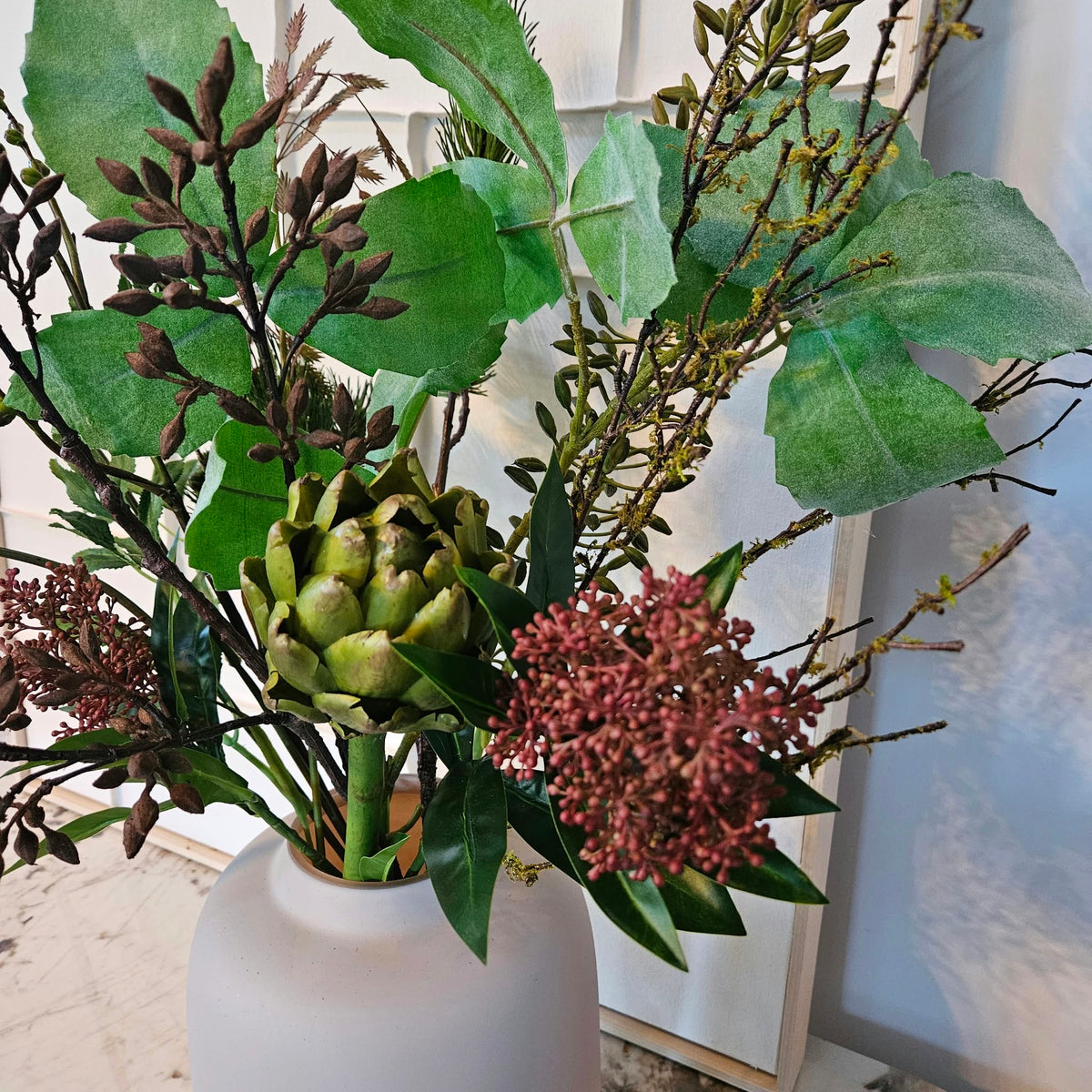 Close-up van Noma Sola kunstboeket met artisjok en rode bloemen